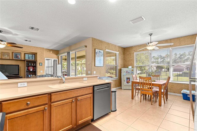 kitchen featuring sink, dishwasher, a textured ceiling, and light tile patterned floors