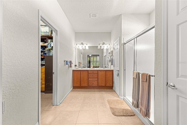 bathroom with vanity, a textured ceiling, tile patterned flooring, and a shower with door