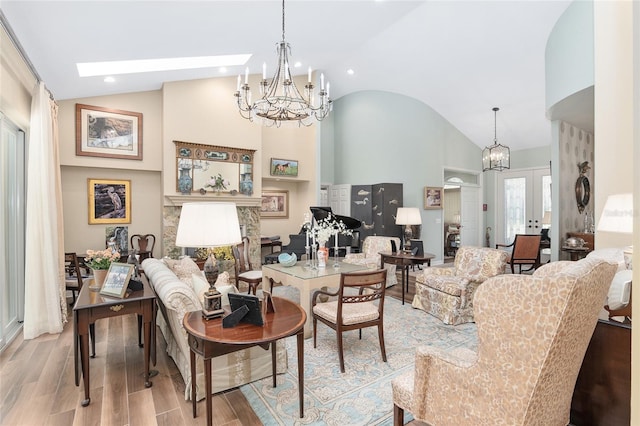 living room with french doors, light hardwood / wood-style floors, high vaulted ceiling, and a skylight