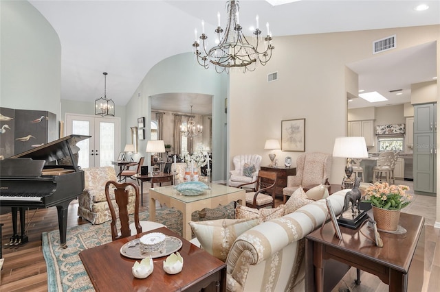 living room featuring high vaulted ceiling, light wood-type flooring, and a skylight