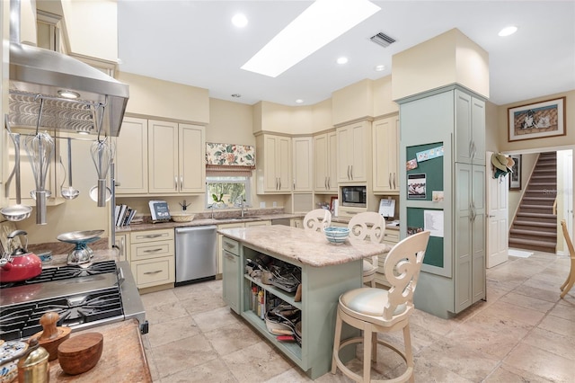 kitchen featuring light stone countertops, cream cabinets, a center island, stainless steel appliances, and a breakfast bar