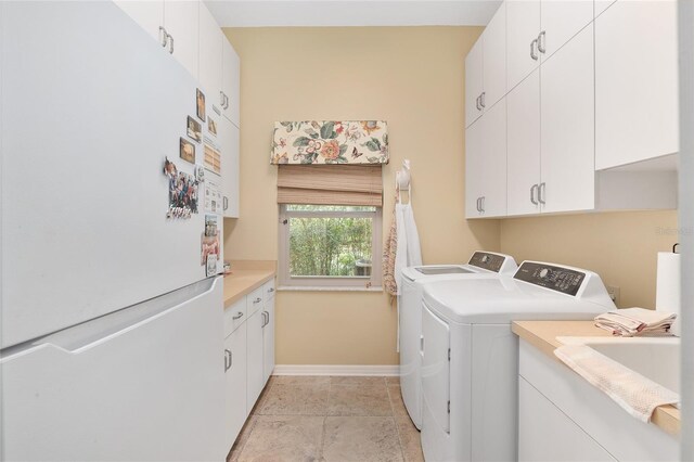 clothes washing area featuring washing machine and clothes dryer, cabinet space, and baseboards
