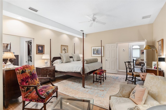 bedroom with a spacious closet, a closet, light wood-type flooring, and ceiling fan