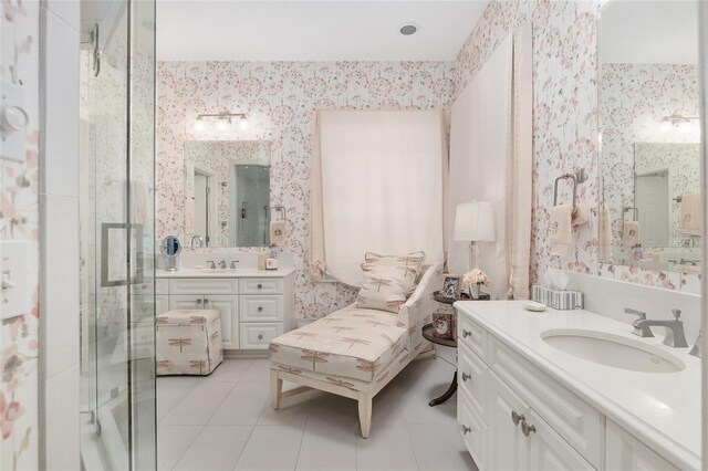 bathroom with wallpapered walls, tile patterned flooring, a shower stall, and two vanities