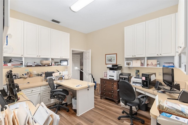 office with built in desk and light wood-type flooring