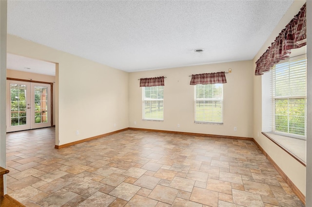 spare room featuring french doors, a healthy amount of sunlight, and a textured ceiling