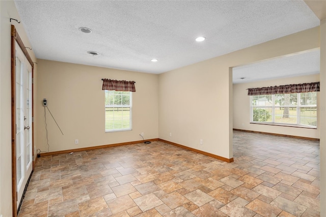 unfurnished room featuring a textured ceiling and plenty of natural light