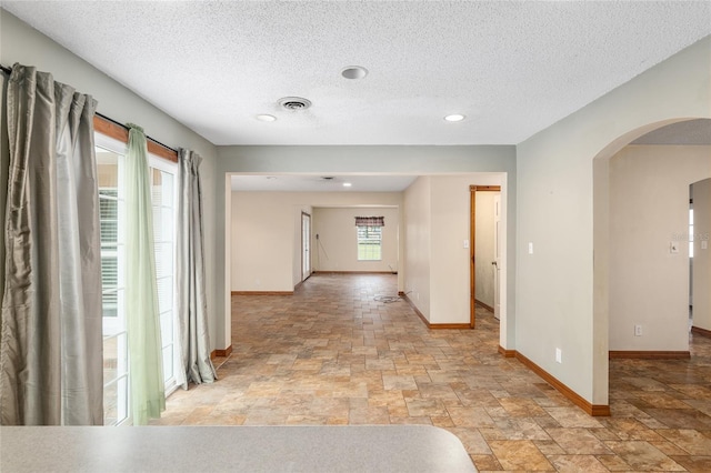 corridor featuring a textured ceiling and plenty of natural light