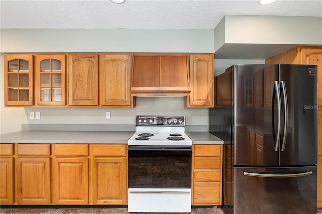 kitchen with electric range oven, stainless steel fridge, custom range hood, and a textured ceiling