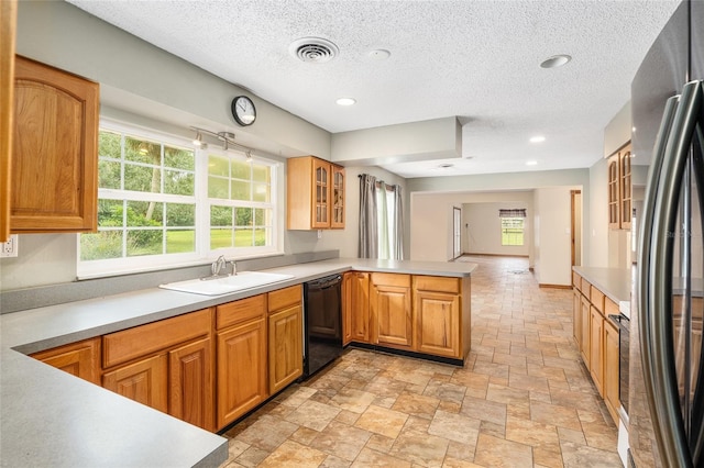 kitchen featuring sink, dishwasher, a textured ceiling, kitchen peninsula, and stainless steel refrigerator