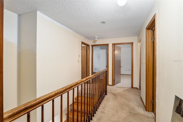 hall with a textured ceiling and light colored carpet