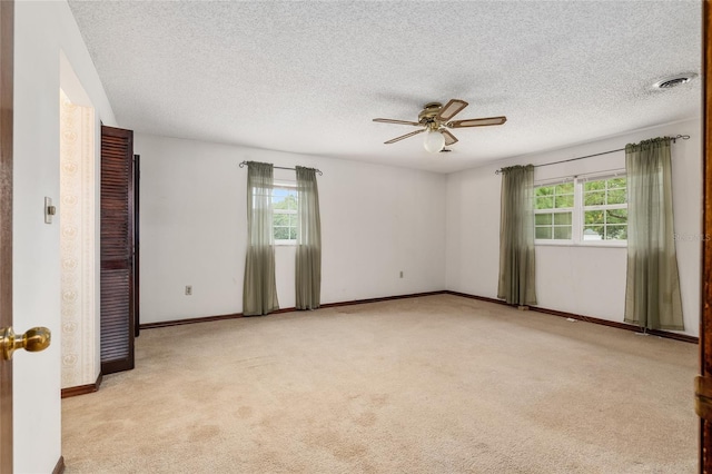 carpeted spare room featuring ceiling fan, a textured ceiling, and plenty of natural light