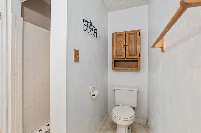 bathroom with a tile shower, toilet, a textured ceiling, and tile patterned flooring