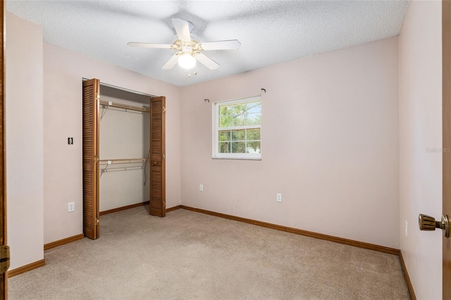 unfurnished bedroom featuring a closet, ceiling fan, a textured ceiling, and light colored carpet