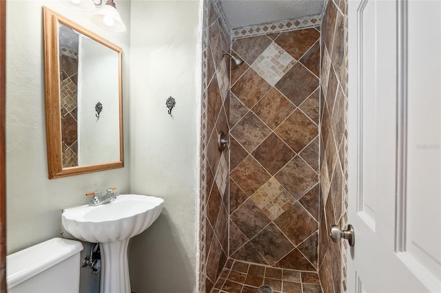 bathroom with a tile shower and toilet