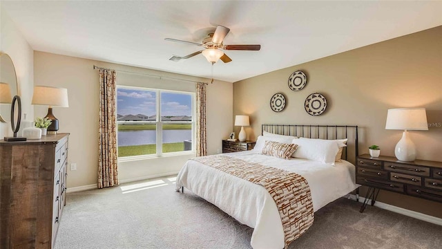 carpeted bedroom featuring a water view and ceiling fan