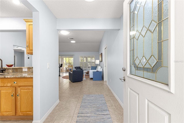 entryway with light tile patterned floors and a textured ceiling