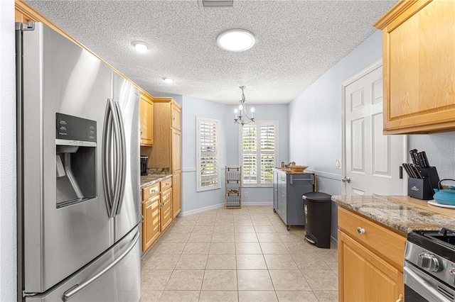 kitchen with stainless steel fridge, stove, light stone counters, and a chandelier