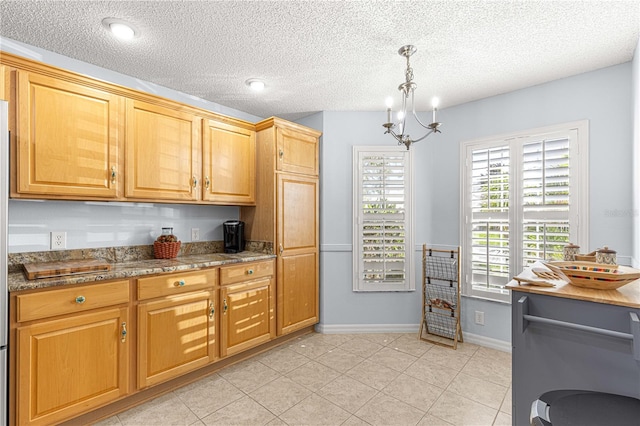 kitchen featuring pendant lighting, dark stone counters, an inviting chandelier, a textured ceiling, and light tile patterned flooring