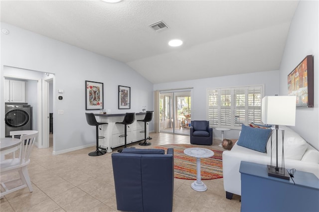 living room featuring light tile patterned flooring, washer / dryer, and lofted ceiling