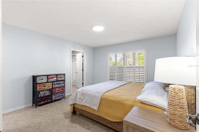 bedroom with ensuite bathroom and a textured ceiling