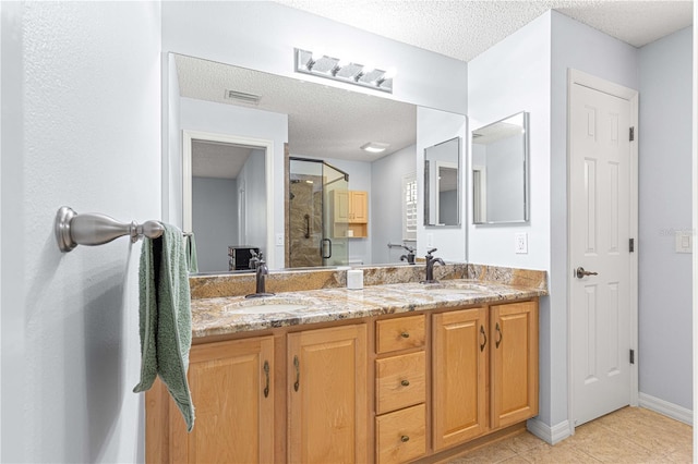 bathroom with tile patterned floors, vanity, a shower with shower door, and a textured ceiling