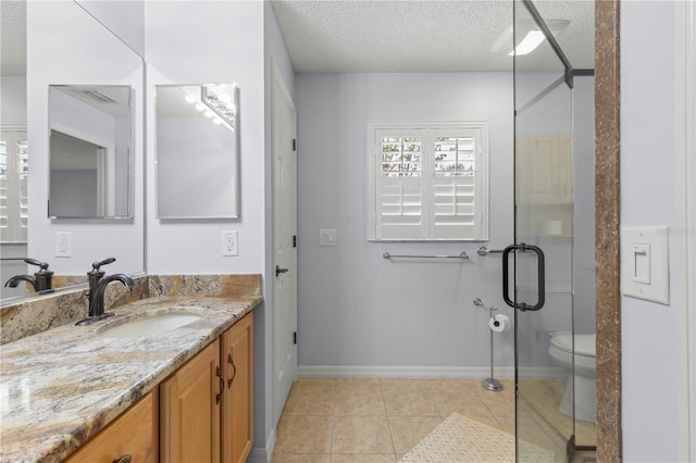 bathroom featuring vanity, a shower with door, tile patterned floors, toilet, and a textured ceiling