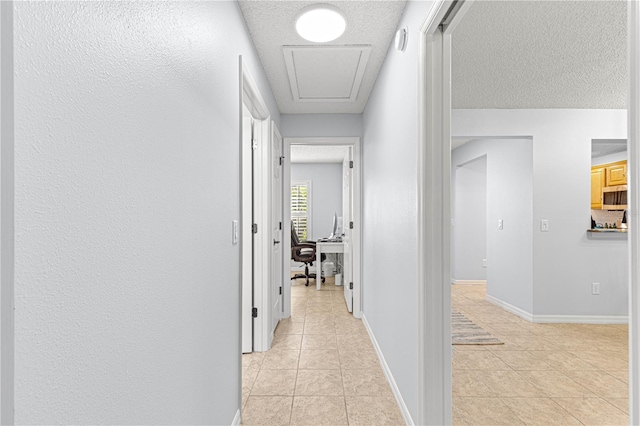 hall featuring a textured ceiling and light tile patterned flooring