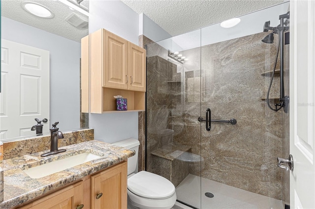 full bath with vanity, a textured ceiling, toilet, and a stall shower