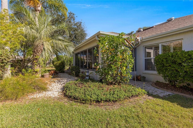 view of side of home featuring a sunroom and a yard