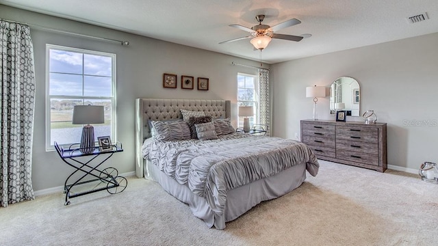 bedroom featuring a textured ceiling, light colored carpet, and ceiling fan