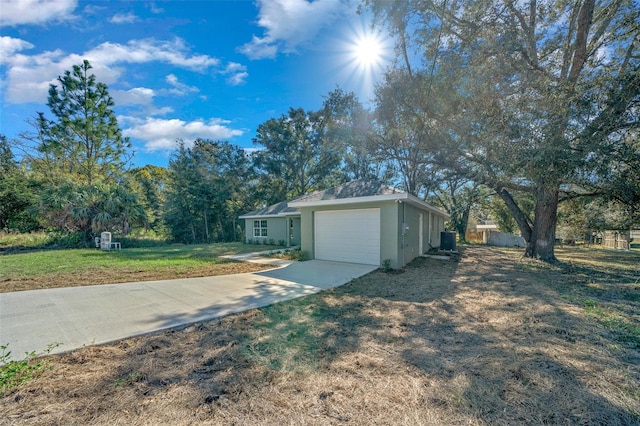 view of front of home featuring a front lawn, central AC unit, and a garage