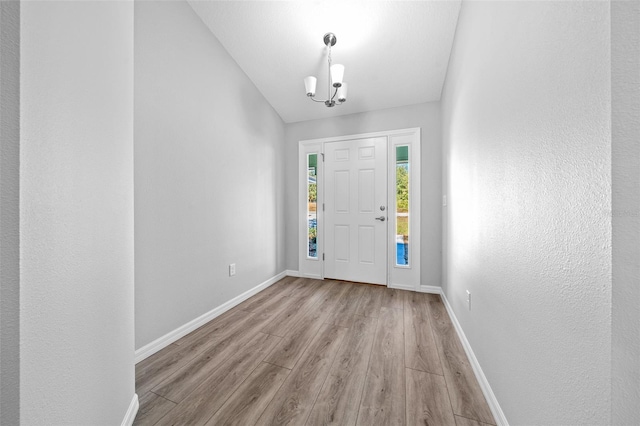 foyer featuring light hardwood / wood-style flooring, a chandelier, and vaulted ceiling