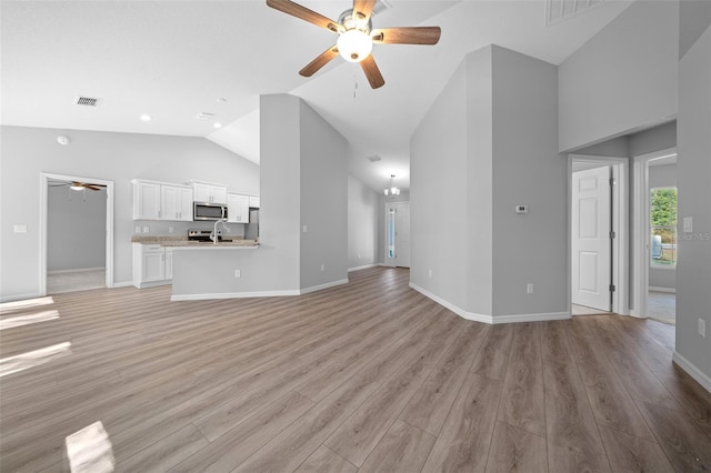 unfurnished living room with high vaulted ceiling, light hardwood / wood-style flooring, ceiling fan, and sink