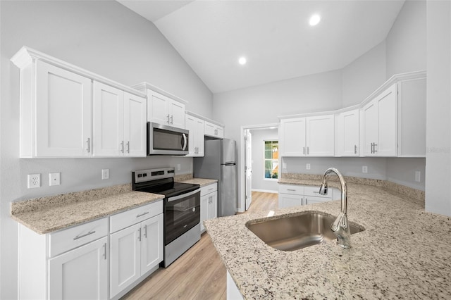 kitchen with white cabinetry, sink, stainless steel appliances, light hardwood / wood-style flooring, and vaulted ceiling