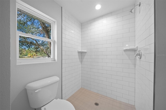 bathroom with a tile shower and toilet