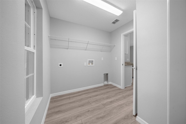 laundry area featuring hookup for an electric dryer, hookup for a washing machine, a textured ceiling, and light hardwood / wood-style floors