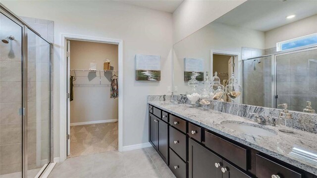 full bath with a sink, a stall shower, a spacious closet, and tile patterned floors