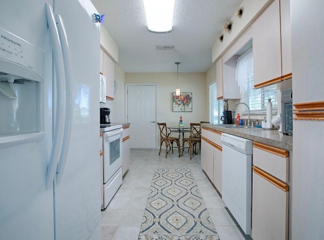 kitchen featuring white appliances, hanging light fixtures, sink, and white cabinets