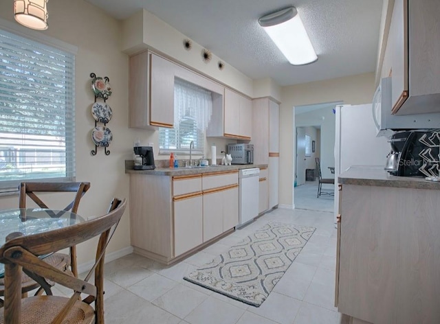 kitchen featuring sink, dishwasher, a textured ceiling, and light tile patterned floors