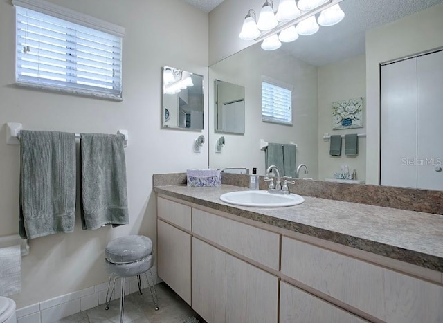 bathroom with vanity, a textured ceiling, a healthy amount of sunlight, and tile patterned floors