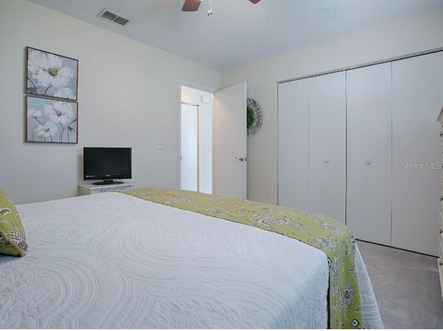 bedroom with a textured ceiling, carpet flooring, a closet, and ceiling fan