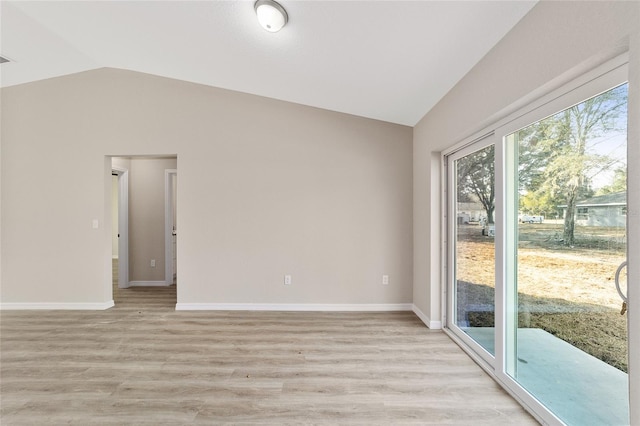 spare room with lofted ceiling and light wood-type flooring