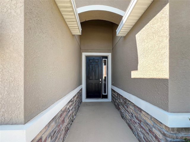 entrance to property with stone siding and stucco siding