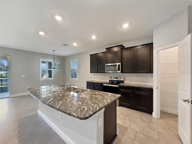 kitchen with sink, appliances with stainless steel finishes, dark brown cabinets, and a kitchen island with sink