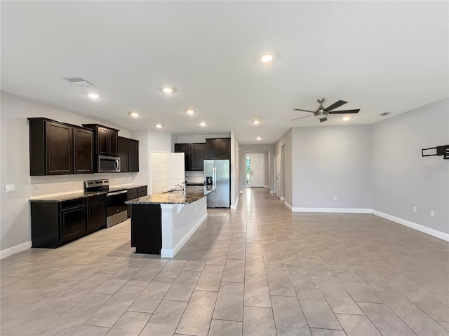 kitchen featuring ceiling fan, an island with sink, light stone countertops, sink, and stainless steel appliances