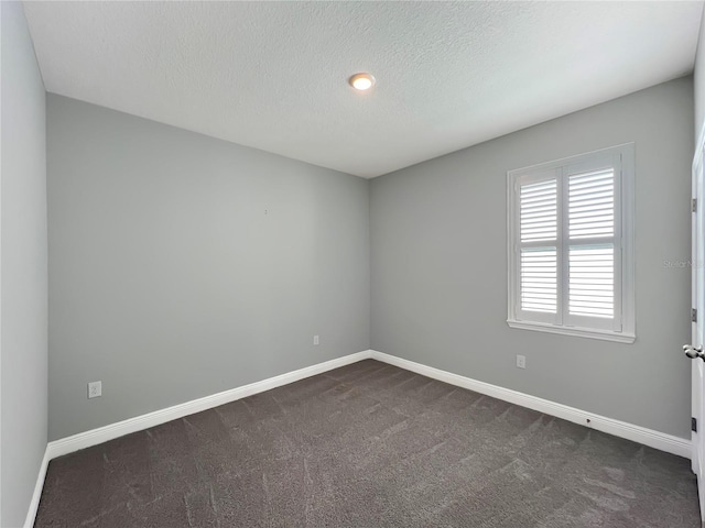 empty room featuring a textured ceiling, baseboards, and dark carpet