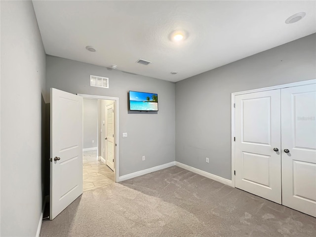 unfurnished bedroom featuring carpet, visible vents, baseboards, and a closet