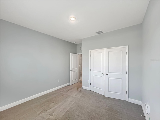 unfurnished bedroom featuring a closet, visible vents, baseboards, and light carpet