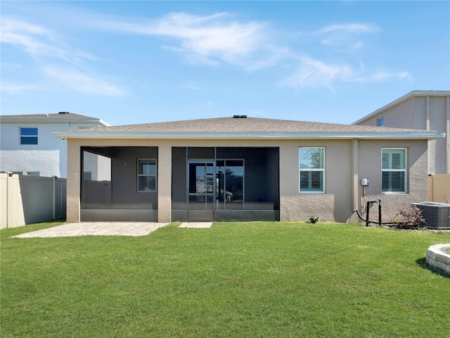 rear view of house with a sunroom, a yard, stucco siding, and fence